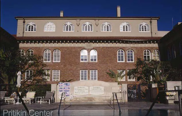 Six-story brick facade of the former Pritikin Center with arched windows above a poolside courtyard