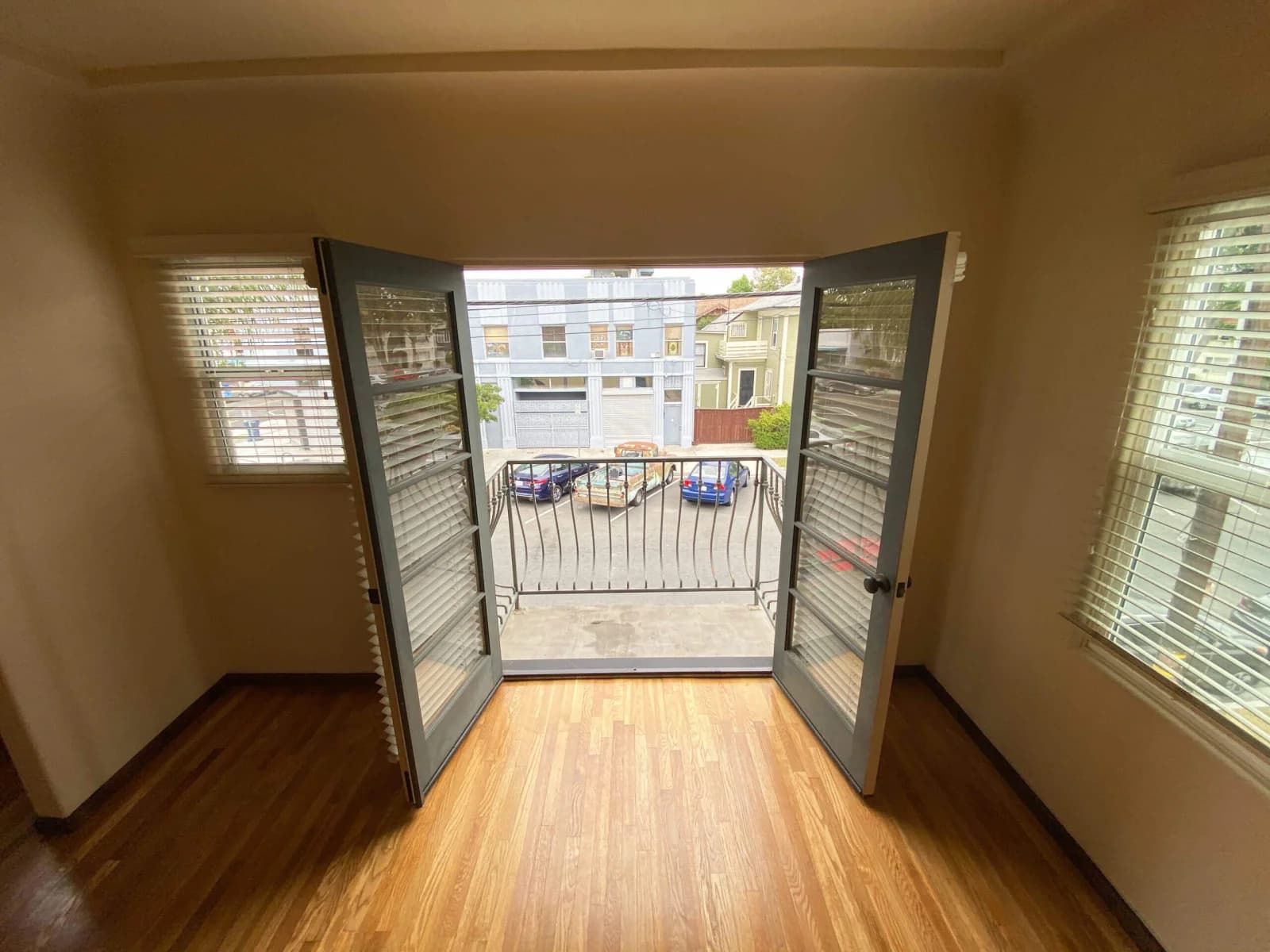 Open French doors leading to a railed balcony off a refinished oak-floored room at Broadway Lofts